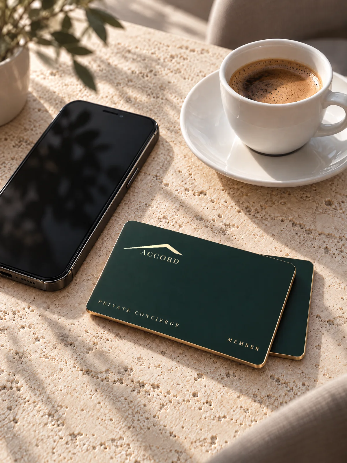 The Private Concierge Card next to a smartphone and an espresso on pale natural stone
